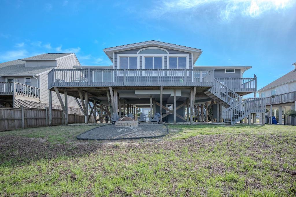 a large house with a deck and a yard at Late For The Sky in Caswell Beach