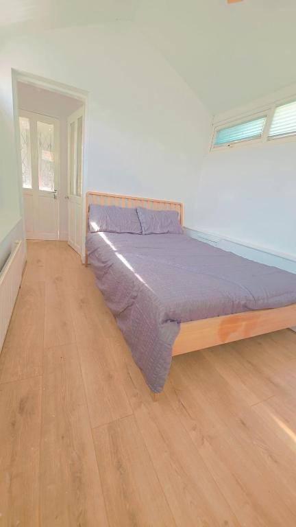 a large bed in a room with a wooden floor at Glory room ensuite in Slough