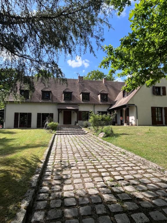 a large white house with a brick driveway at Chambres d'hôtes les Boulommiers in Samois-sur-Seine