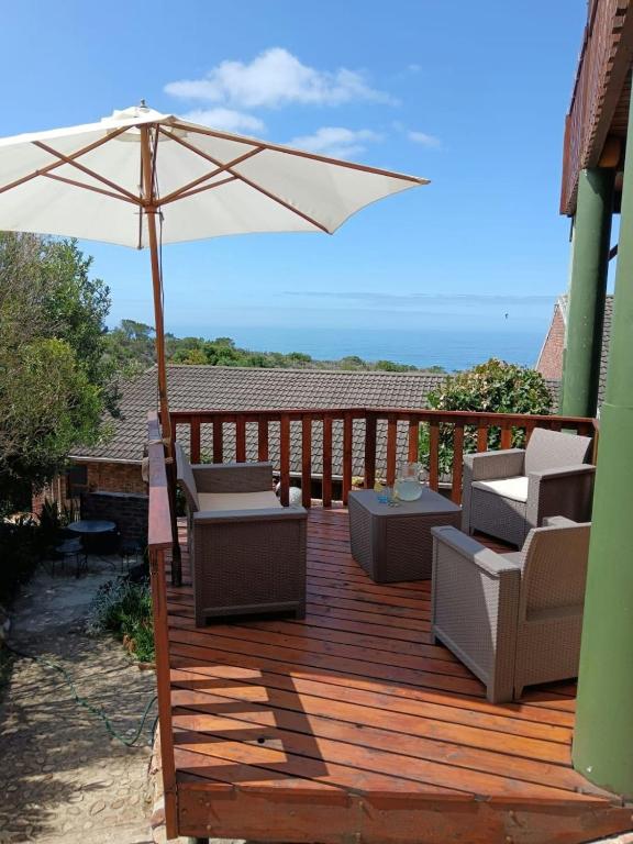a wooden deck with chairs and an umbrella at Rusibiki in Gqeberha
