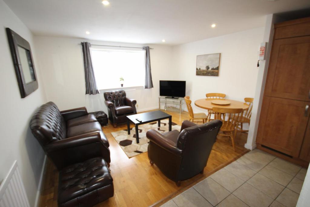 a living room with leather furniture and a table at Bath Road Place in Harmondsworth