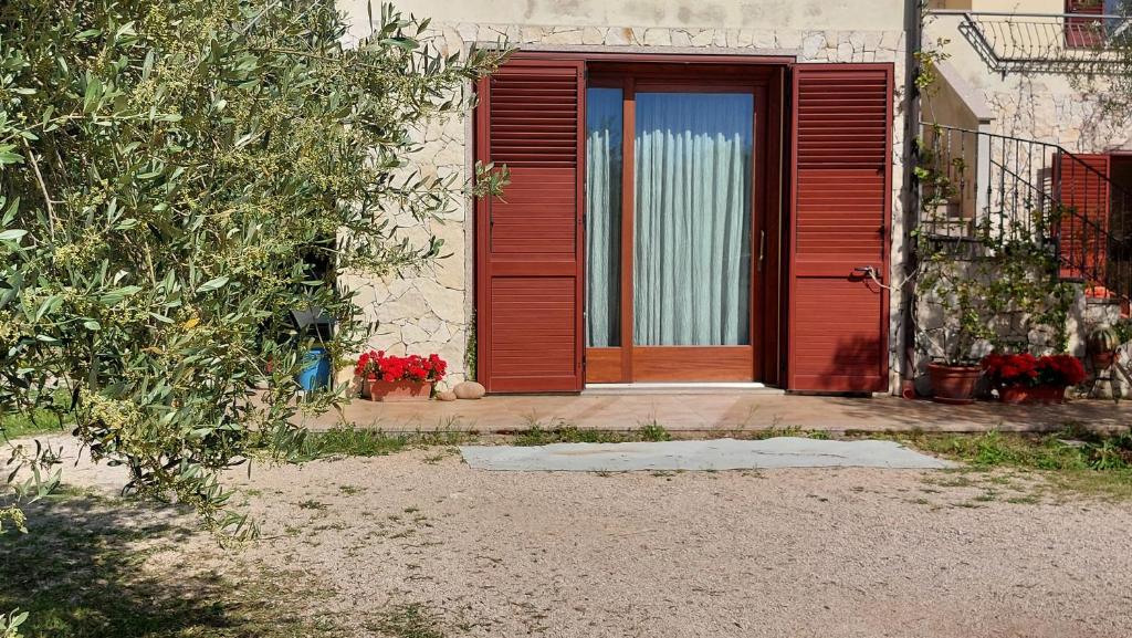 a red door on a house with red flowers at Residence degli ulivi in Ossi