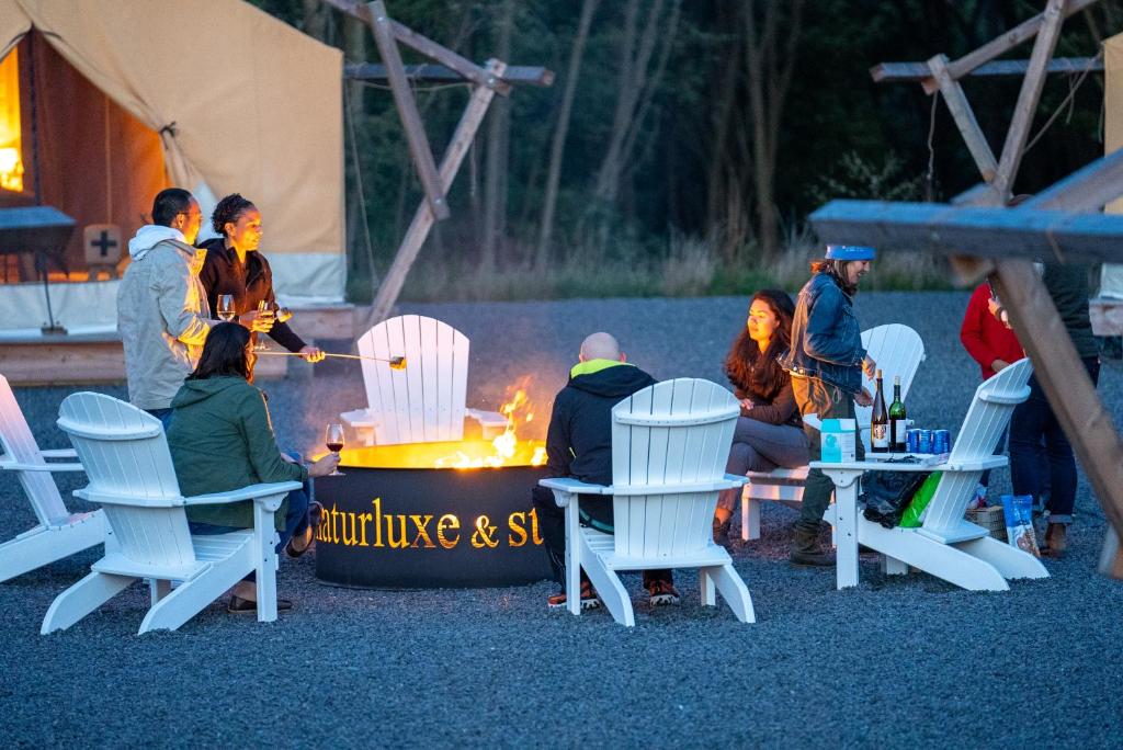 a group of people sitting around a fire in a tent at Naturluxe & Stars in Watkins Glen