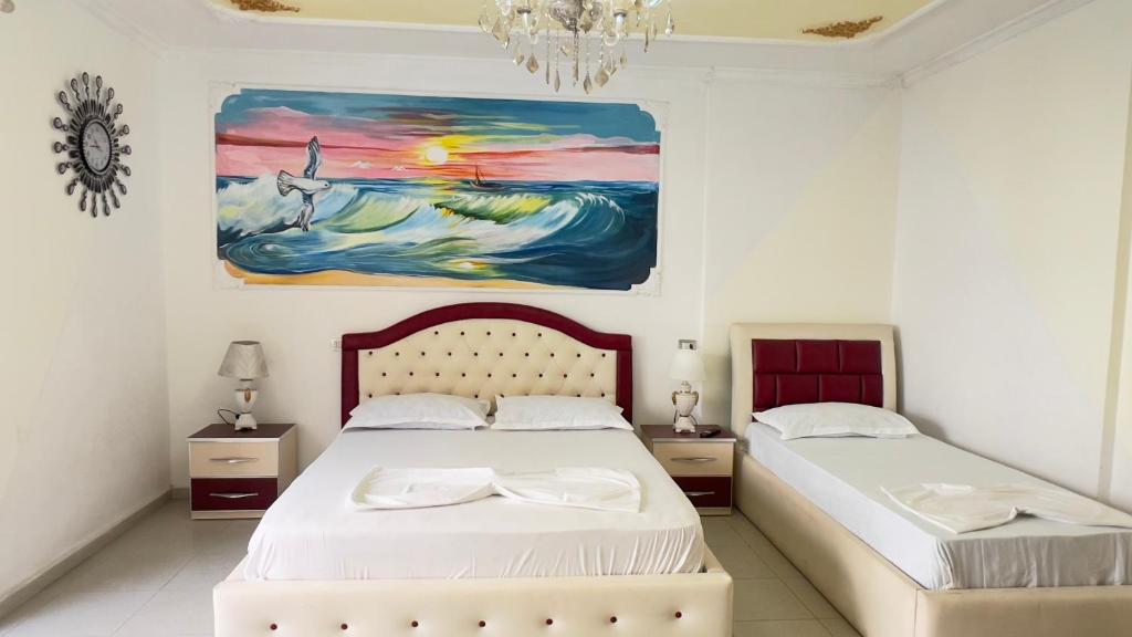 a bedroom with two beds and a painting on the wall at Villa Kliven in Durrës