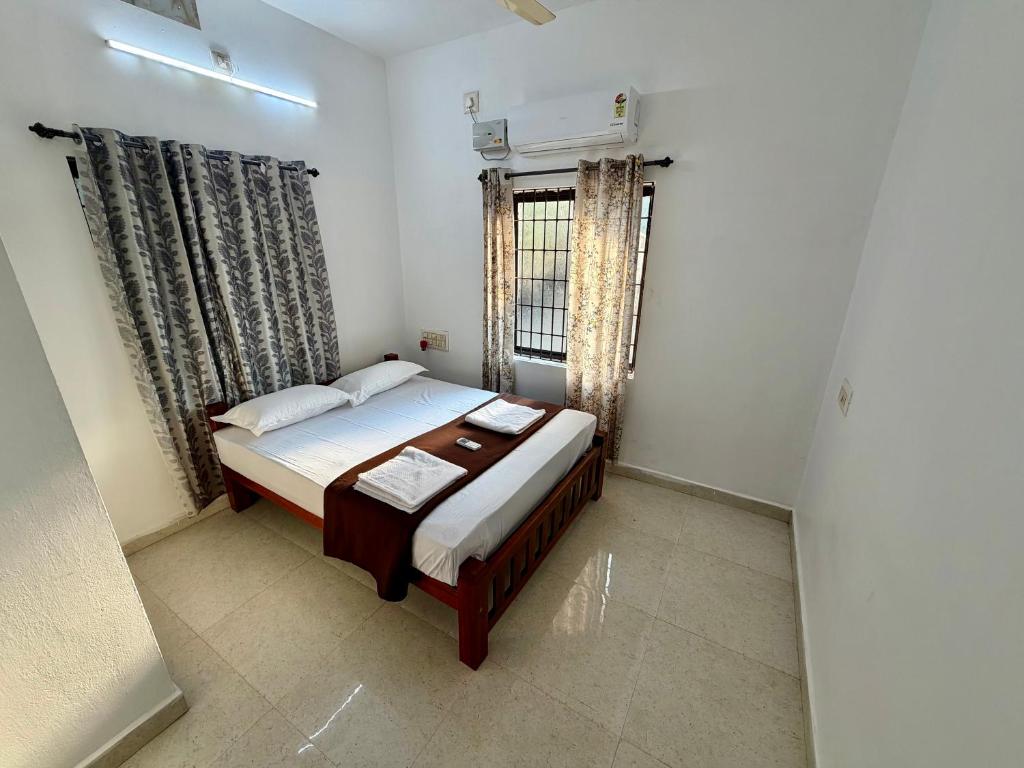 a small bedroom with a bed and a window at Nanasu Home stay in Malpe