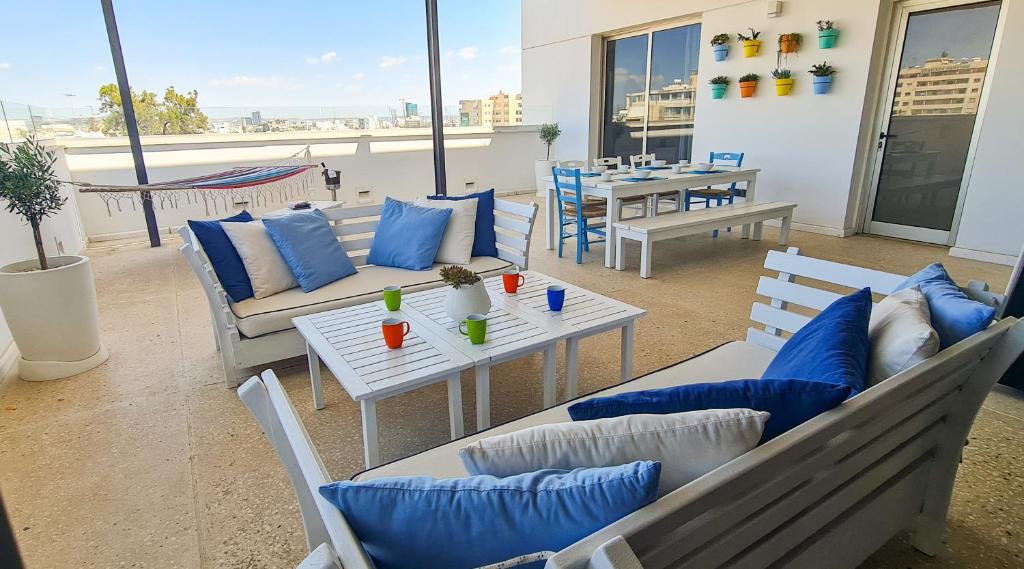 a patio with couches and a table with blue pillows at City Penthouse in Larnaca