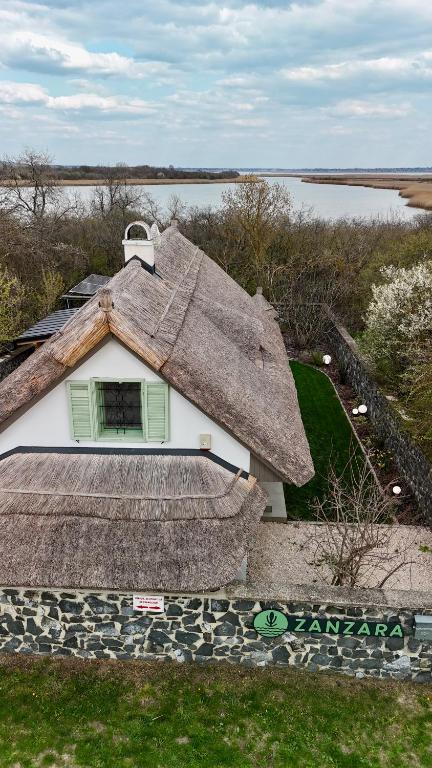 a house with a thatched roof on top of it at Zanzara Guesthouse in Pákozd