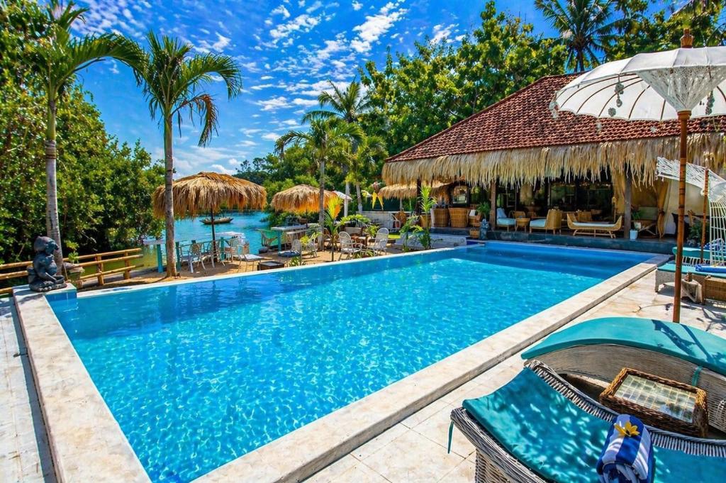 a swimming pool in a resort with chairs and umbrellas at Alinn Villas in Nusa Lembongan