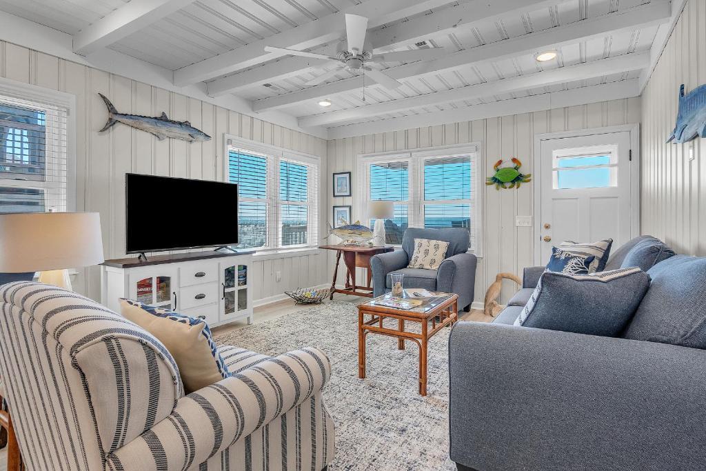 a living room with two couches and a flat screen tv at Lowe Tide in Oak Island