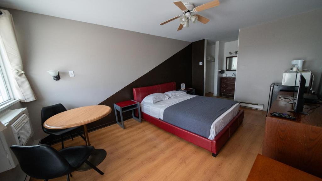 a bedroom with a bed and a table and chairs at Motel Giffard in Quebec City