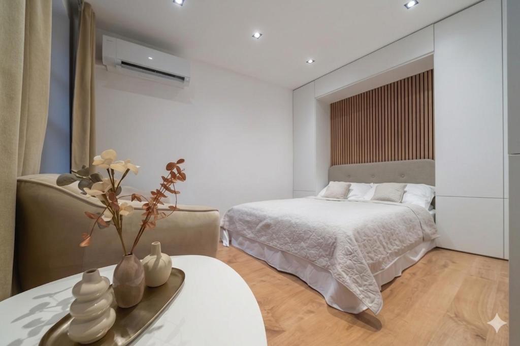 a white bedroom with a bed and a table with a table sidx sidx at Apartmán Daniel in Levoča