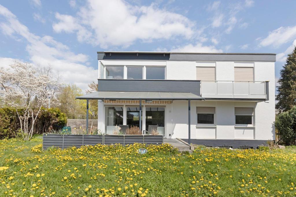 a white house on a hill with a field of flowers at Ferienwohnungen Hirsch Schwarzwald in Bad Dürrheim