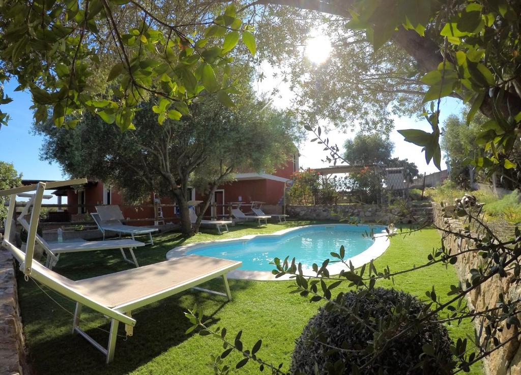 ein Swimmingpool im Garten mit einer Bank in der Unterkunft Su Kiniperu in Maracalagonis