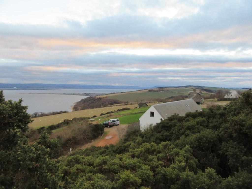a car parked on a hill next to a white building at Kestrel, Longhouse Cottages in Rosemarkie