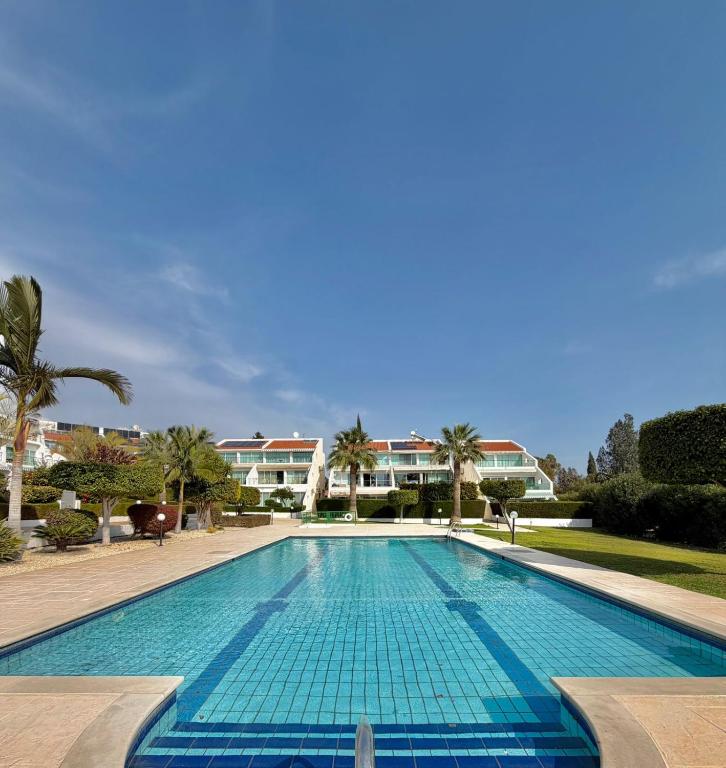 a large swimming pool with palm trees and buildings at Bayview Terraces Cozy 1BR Haven in Limassol