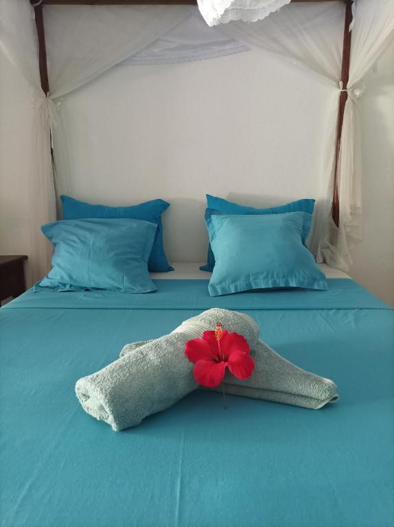 a bedroom with a blue bed with a red flower on it at Chambres d'hôtes Villa Les Orchidées Chez Ago in Sainte Marie