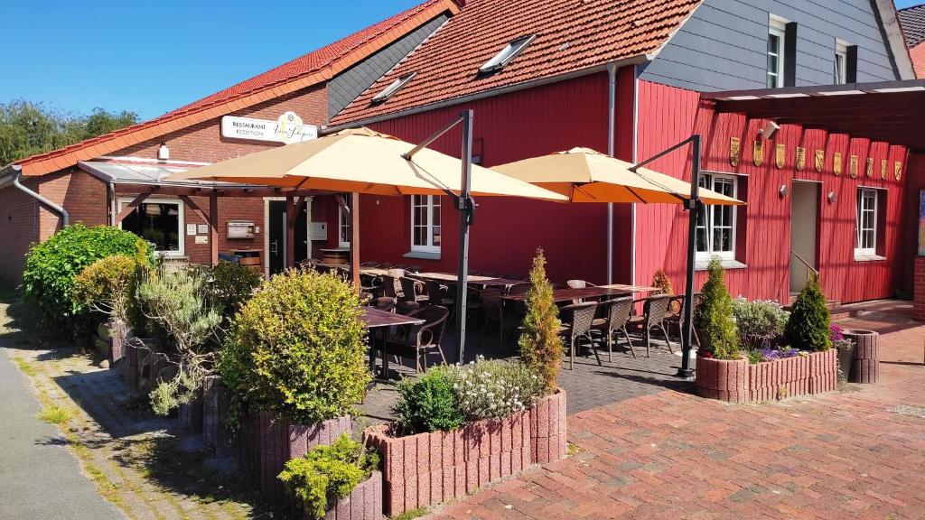 a restaurant with tables and umbrellas in front of a building at Landhotel Vosse-Schepers in Rhede