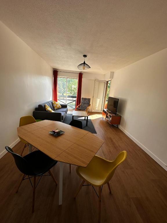 a living room with a wooden table and chairs at Appartement Soustons Les marronniers in Soustons
