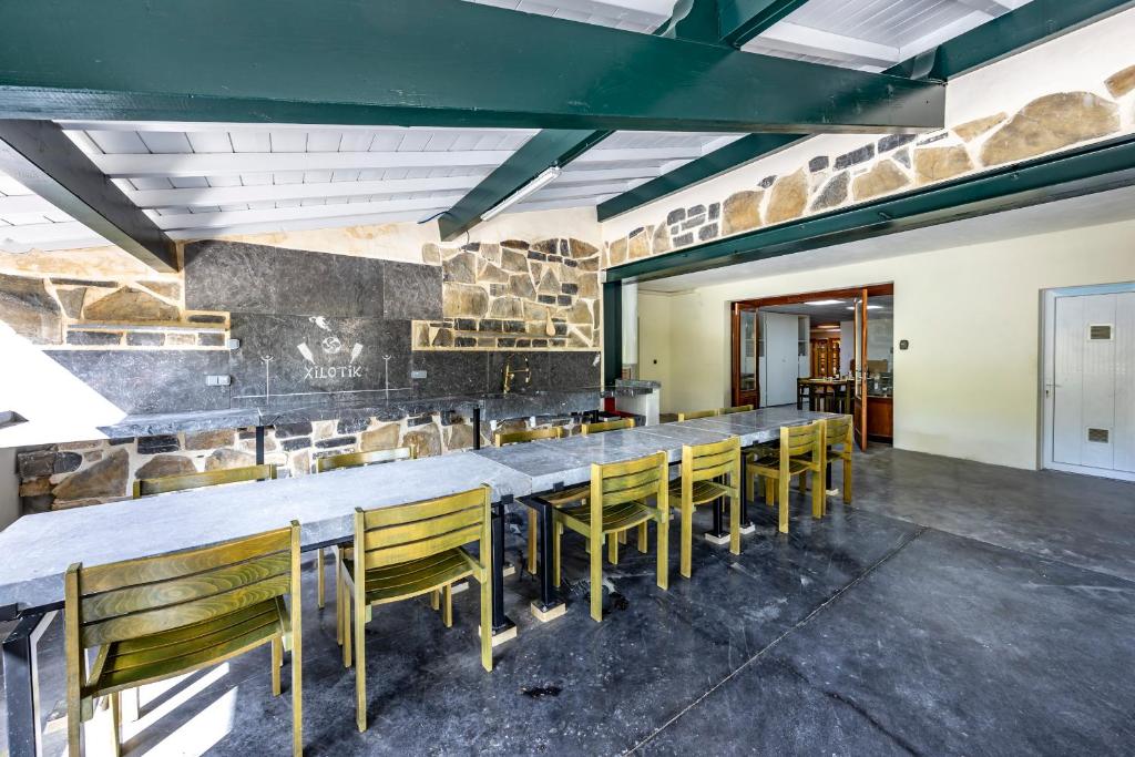 a dining room with a long table and yellow chairs at Le Xilotik Gîte in Espelette