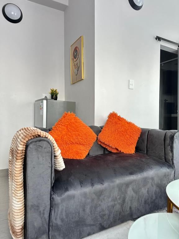 a black leather couch with orange pillows on it at Aegis building in Johannesburg