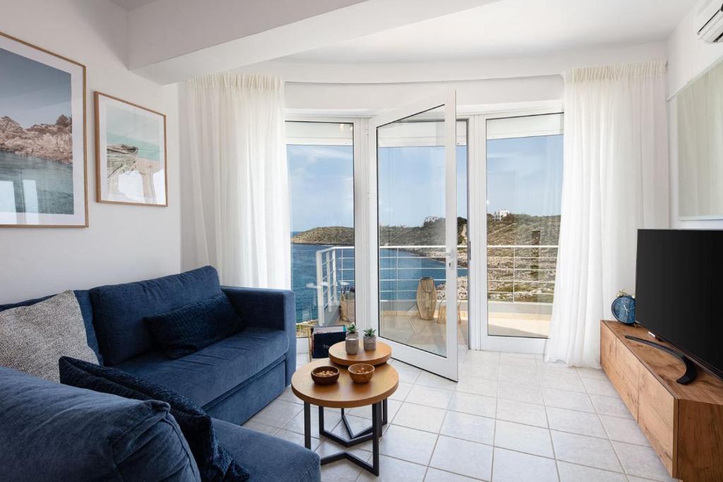 a living room with a blue couch and a television at Tersanas Seaside Apartment in Tersanas