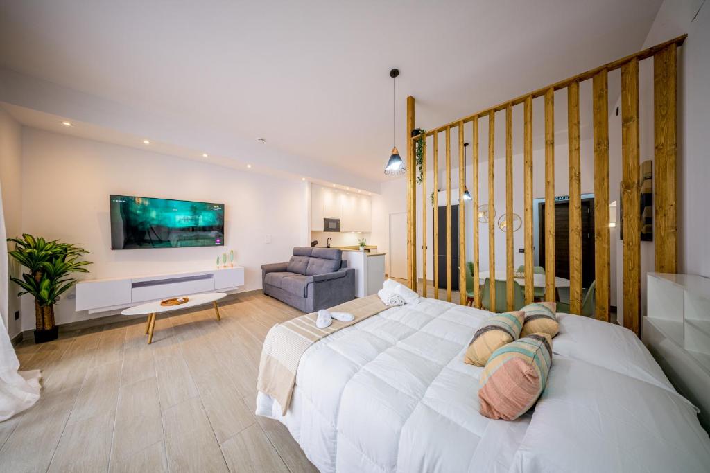a bedroom with a large white bed and a couch at Apartamentos Sibarys in Nerja