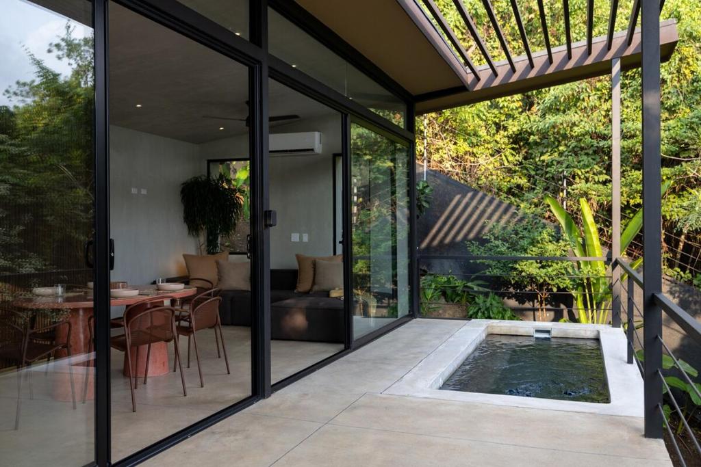 a glass extension of a house with a swimming pool at Garden Treehouse Ikhaya in Refundores
