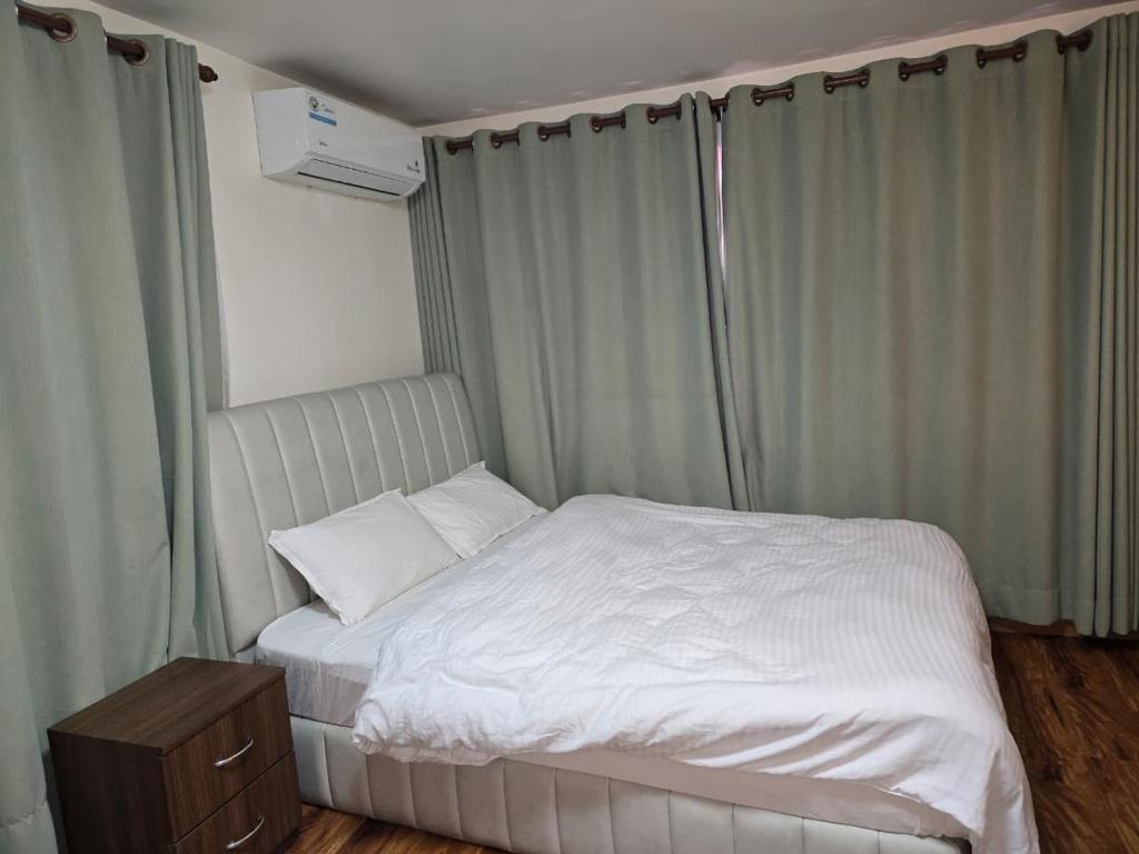 a white bed in a bedroom with curtains at Fu Shang Villa in Kathmandu
