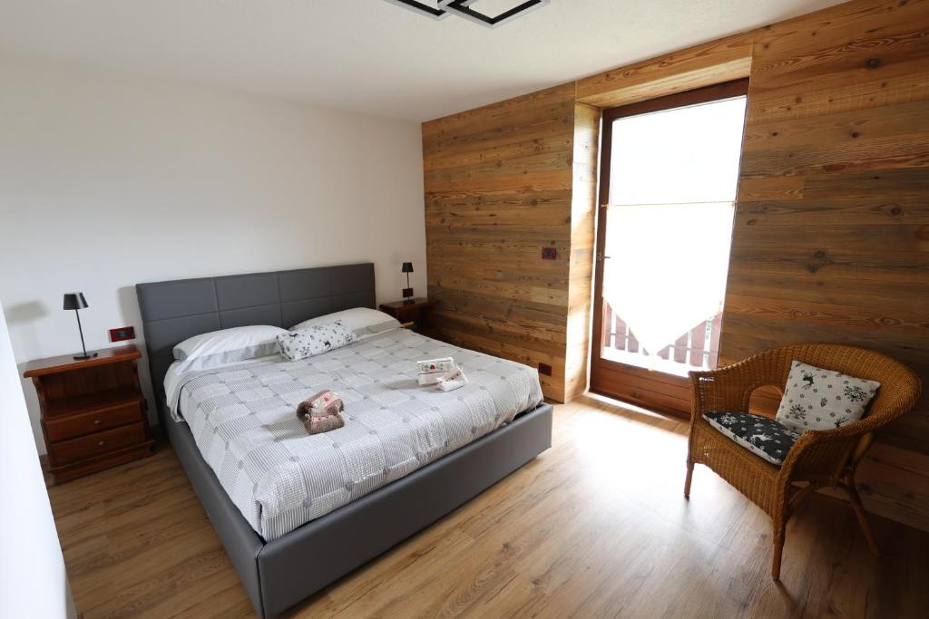 a bedroom with a bed and a window and a chair at Maison Rita e Cello in La Salle