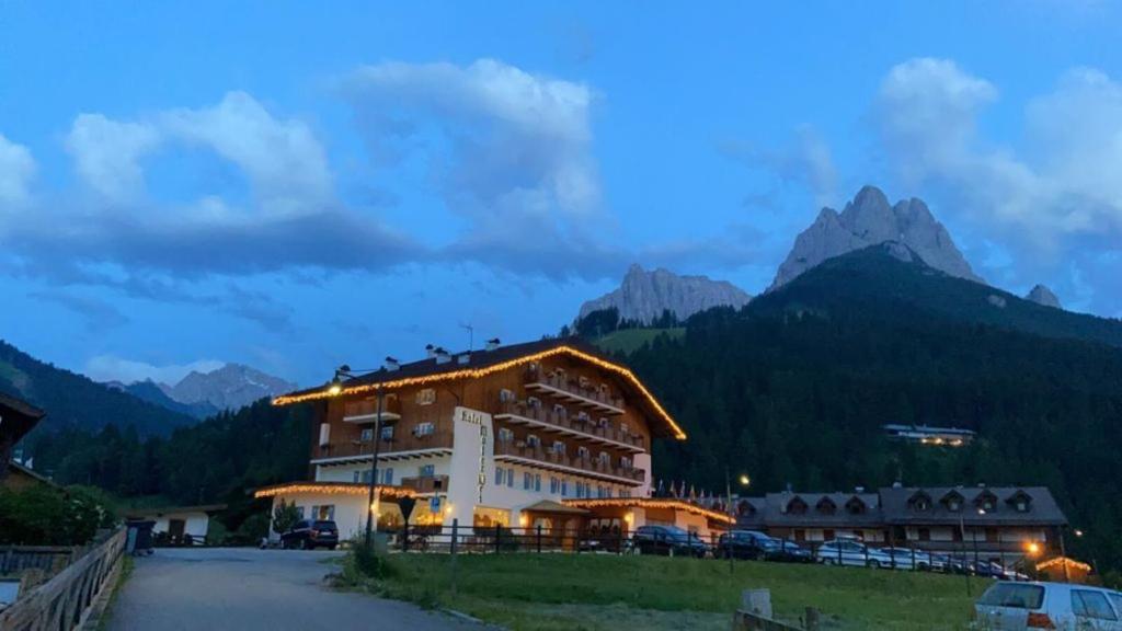 a large building with mountains in the background at Park Hotel Mater Dei in Pozza di Fassa