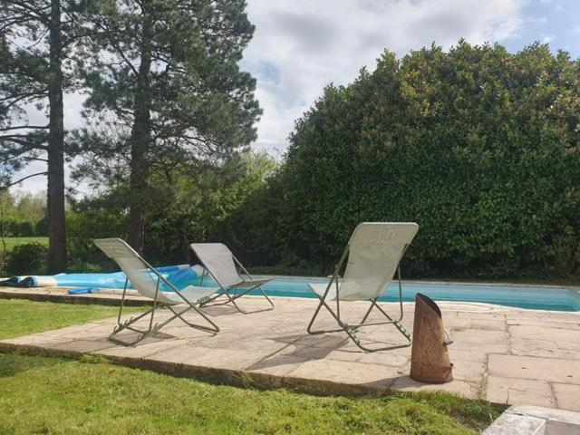 three lawn chairs sitting in front of a pool at Longère 'Nature et Baies' in Montigny