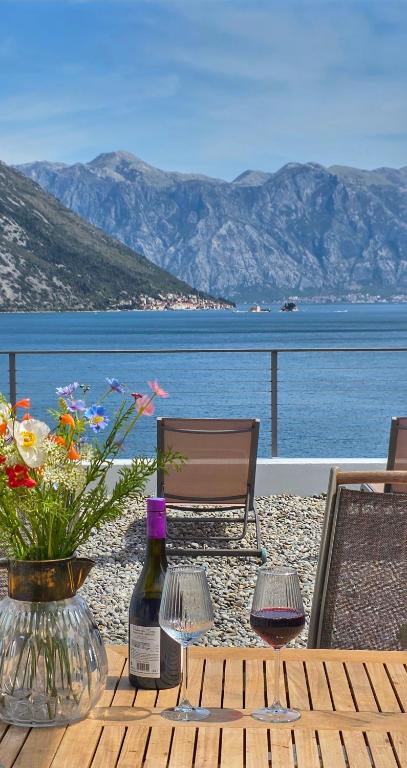a wooden table with a bottle of wine and flowers at Villa Morion with Sauna and Pool in Donji Morinj