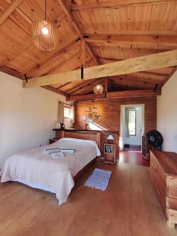 a bedroom with a large bed and wooden ceilings at Chalé Das Quaresmeiras in Aiuruoca