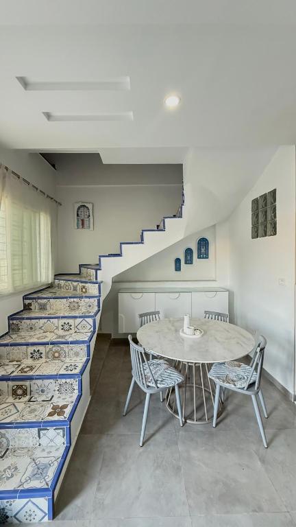 a room with a table and chairs and stairs at Sidi bou duplex in La Goulette