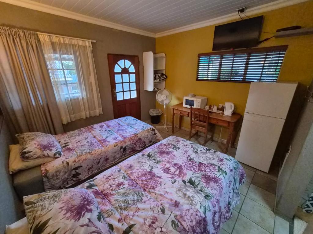 a bedroom with two beds and a desk with a computer at N4 Guest Lodge in Rustenburg
