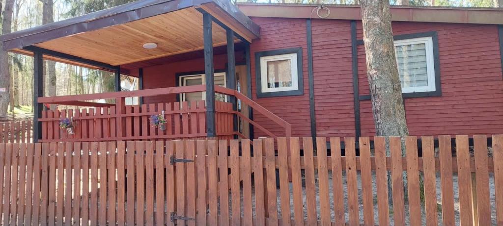 a red house with a wooden fence in front of it at Oleandria-,, Domek Mięta" in Biskupiec