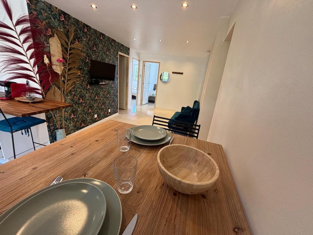a wooden table with two plates and glasses on it at Le Nid du Cotentin - Maison moderne & calme in Les Pieux