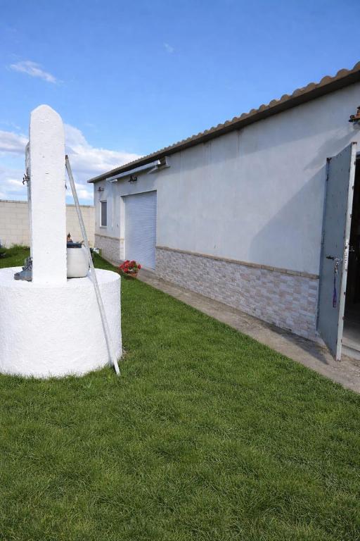 a brick building with a pillar in the grass at La Rocina in Sanlúcar de Barrameda