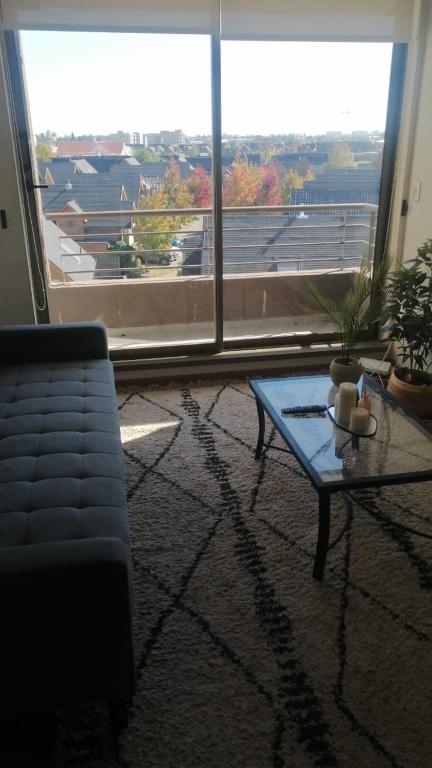 a living room with a couch and a table and a large window at privilegio apart in Los Ángeles