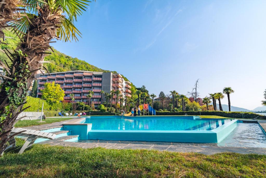 a swimming pool with a hotel in the background at Bissone Campione Lake Pool & Relax in Bissone