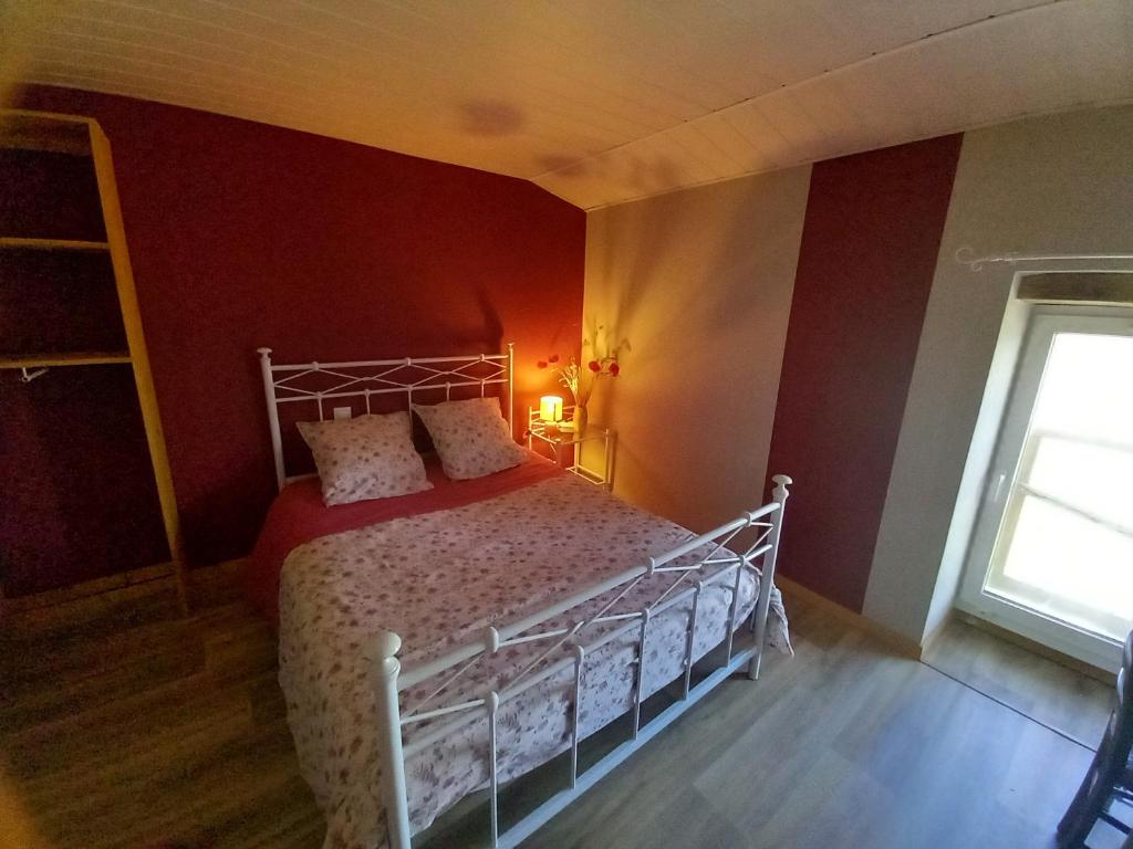 a bedroom with a bed with red walls and a window at Chambre hibiscus in La Roche-sur-Yon