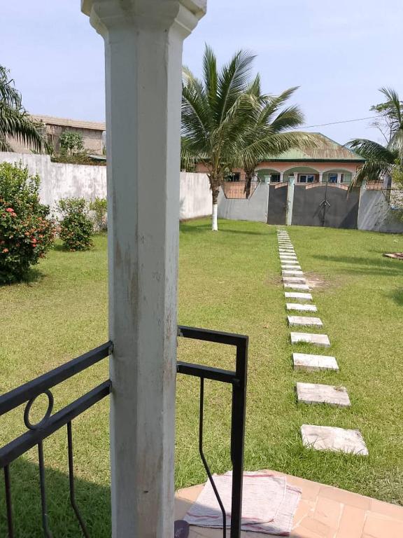 a white column in a yard with a house at La casa in Kribi