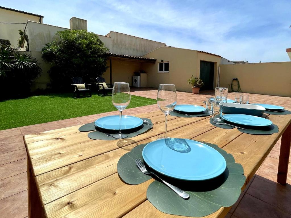 a wooden table with plates and wine glasses on it at Mindelo Beach House in Vila Chã