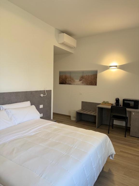a bedroom with a large white bed and a desk at Tesorella guest house in Cassano dʼAdda