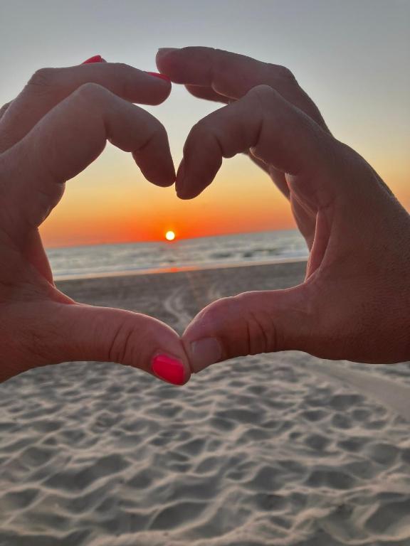 a pair of hands forming a heart on the beach at Mouton Beach Lodge in Petten