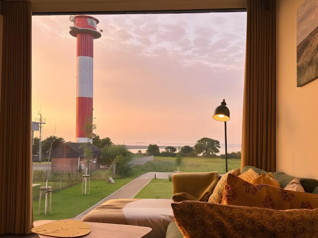 a living room with a view of a lighthouse through a window at Meerglück am Beltblick Fehmarn - FeWo mit Sauna, Blick auf Ostsee und Leuchtturm, nur 150 m zum Meer in Fehmarn