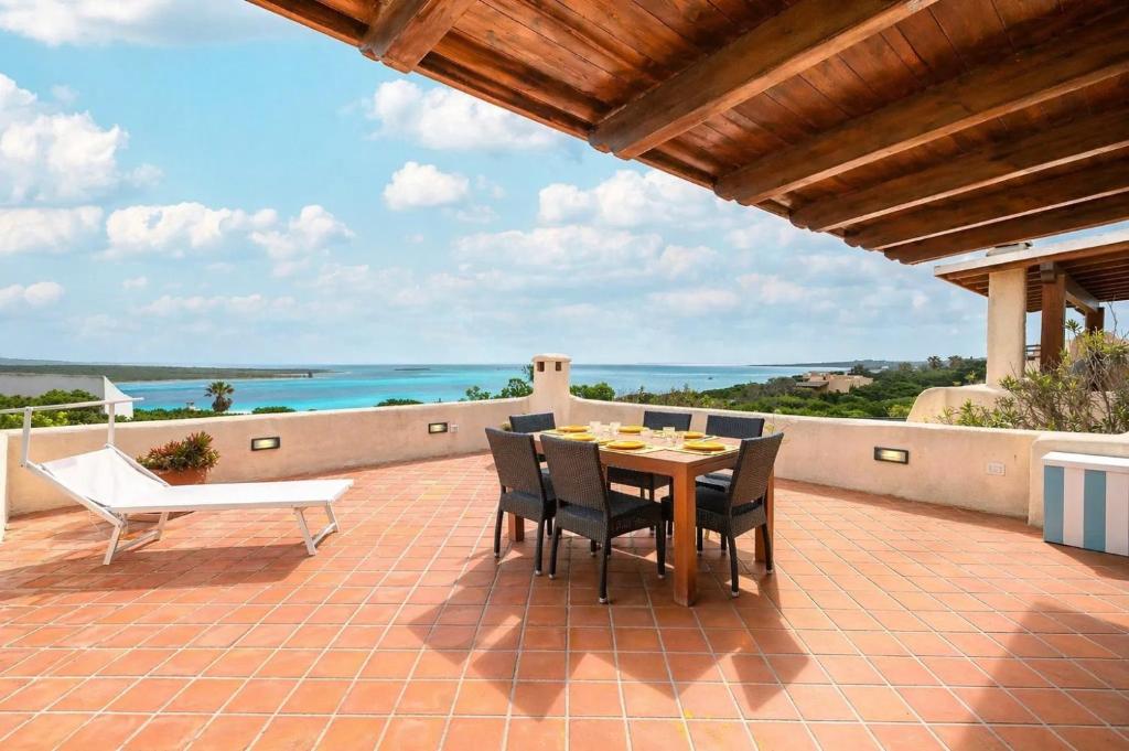 a table and chairs on a patio with a view of the ocean at Casa Marina a 150mt dalla pelosa in Stintino