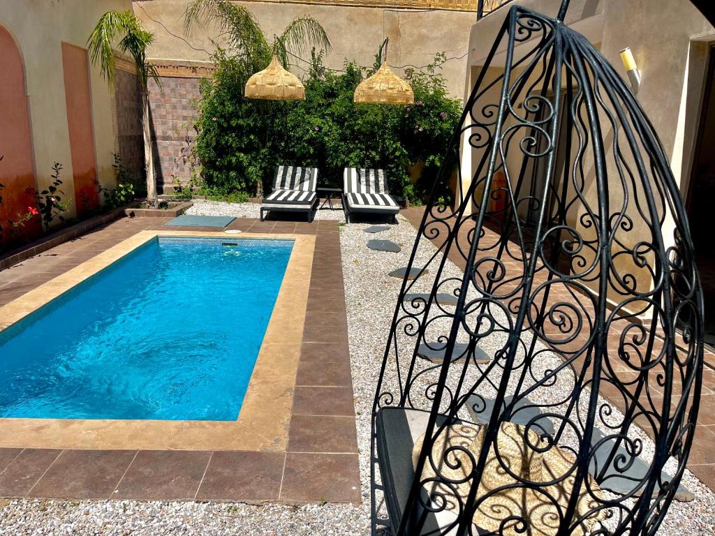a swimming pool with chairs next to a metal fence at Villa Paradis in Marrakesh