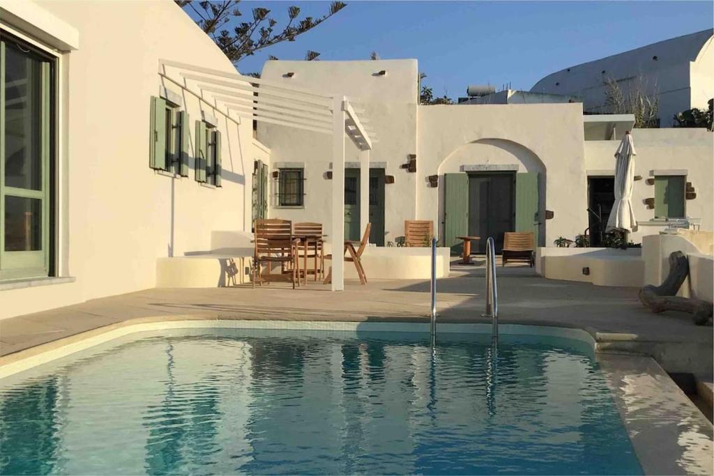 a house with a swimming pool in front of a house at Margarita Studio - Sunset View in Santorini