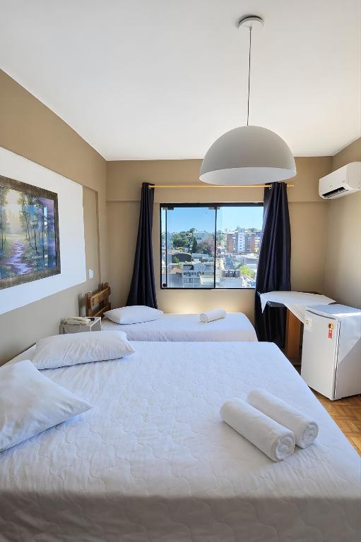 ein Schlafzimmer mit zwei Betten und einem großen Fenster in der Unterkunft Nuevo Hotel in Rivera